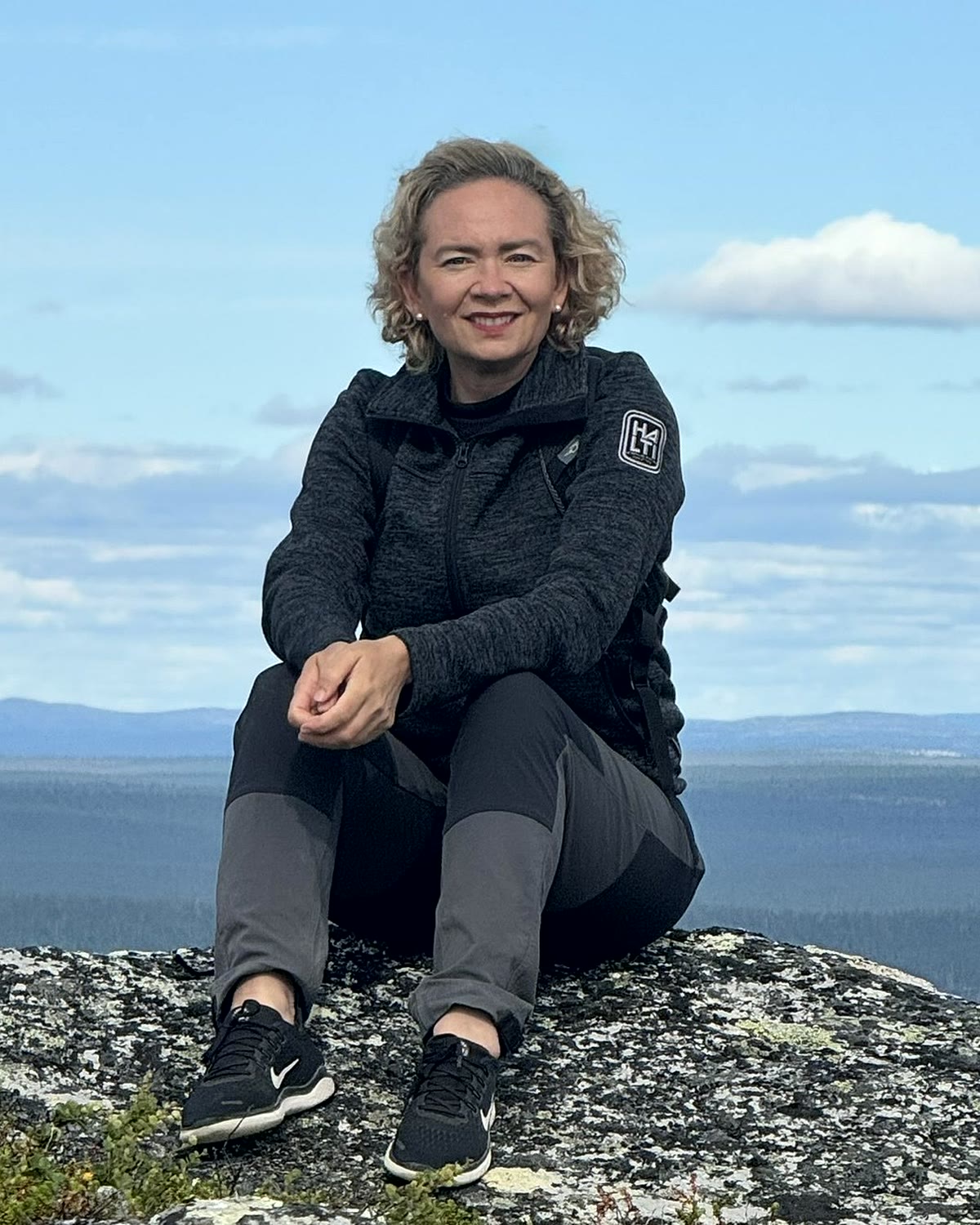 Tarja Stephens seated on a Lapland fell, smiling at the camera
