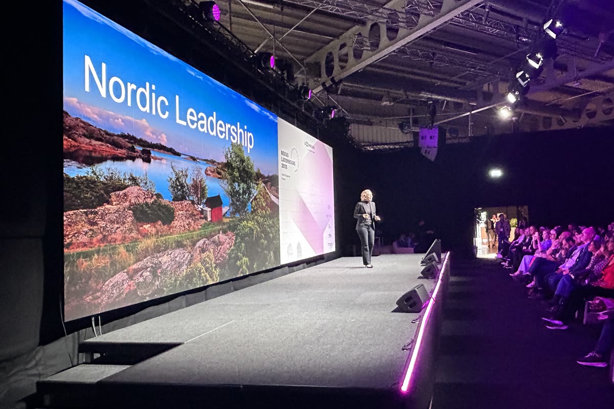 Tarja on stage with a Nordic Leadership slide of a Lapland lake behind her