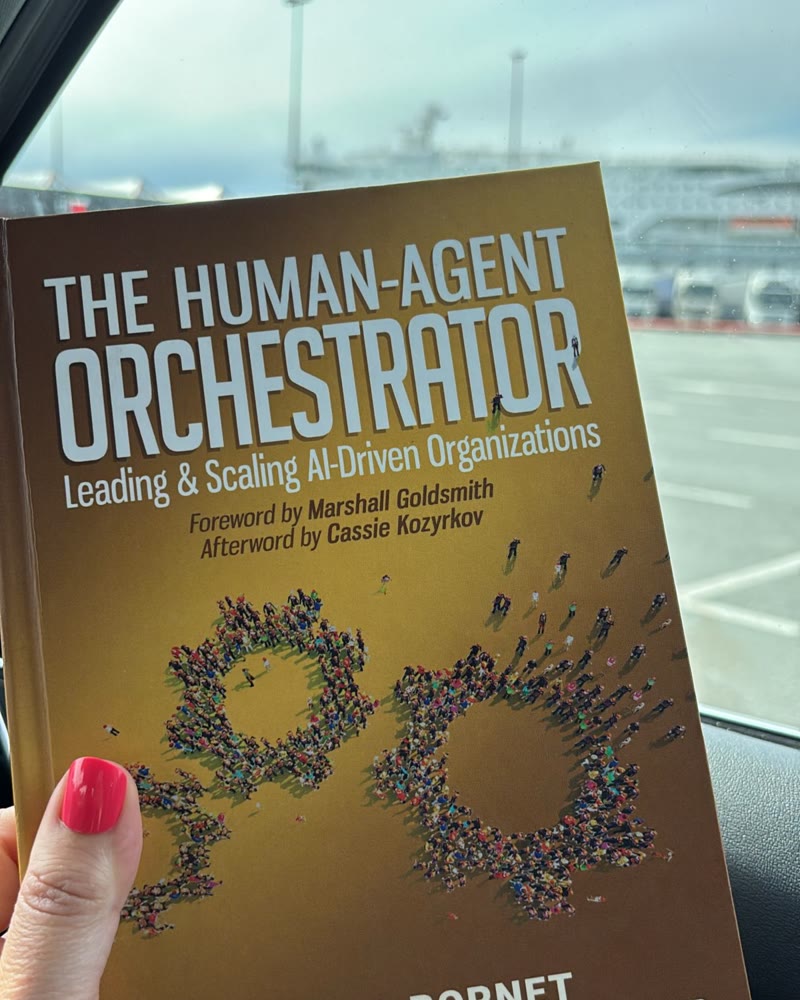 The Human-Agent Orchestrator held up against a car window at a harbour.