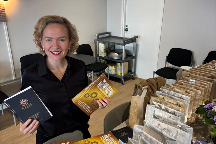Tarja at a table with a stack of the book.