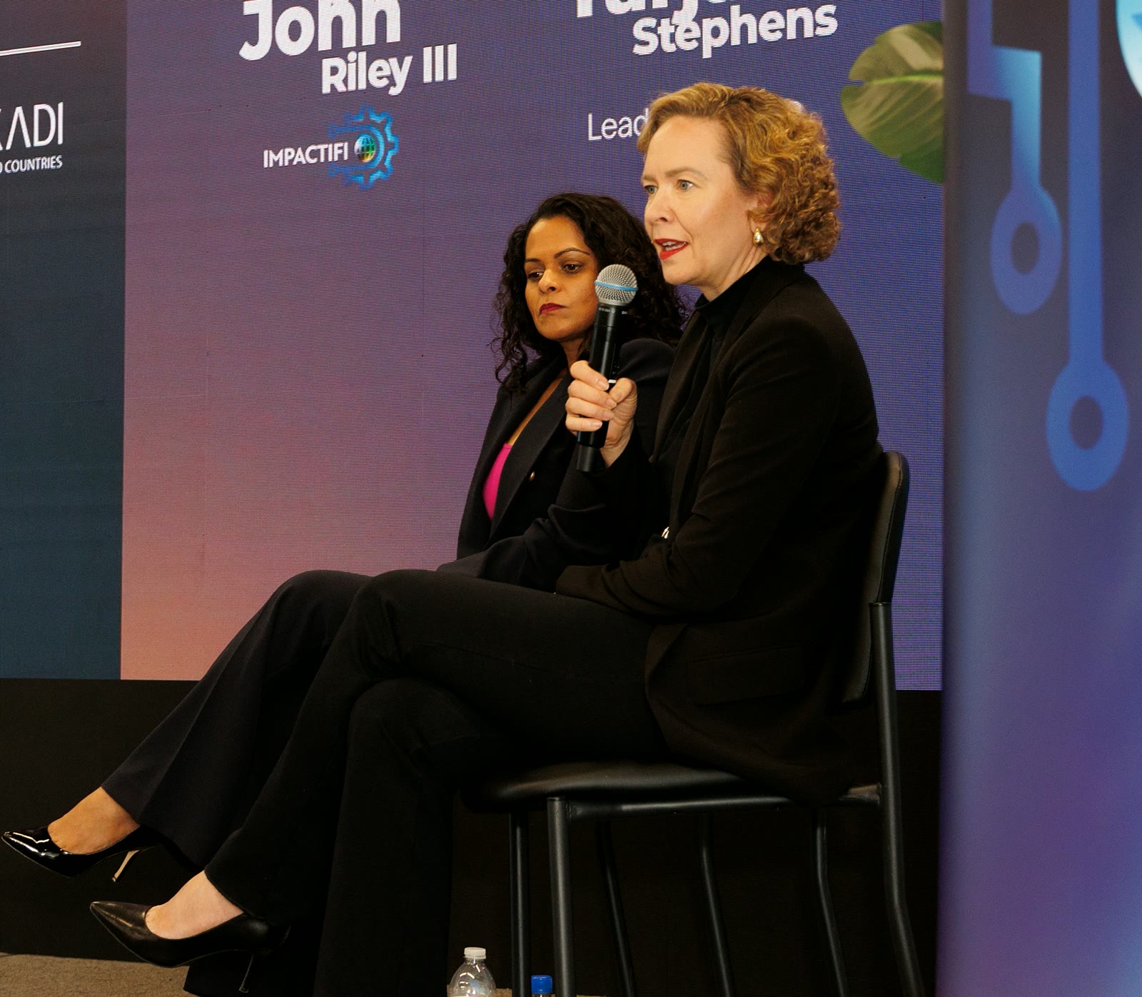 Tarja Stephens speaking into a microphone on a panel in Miami.