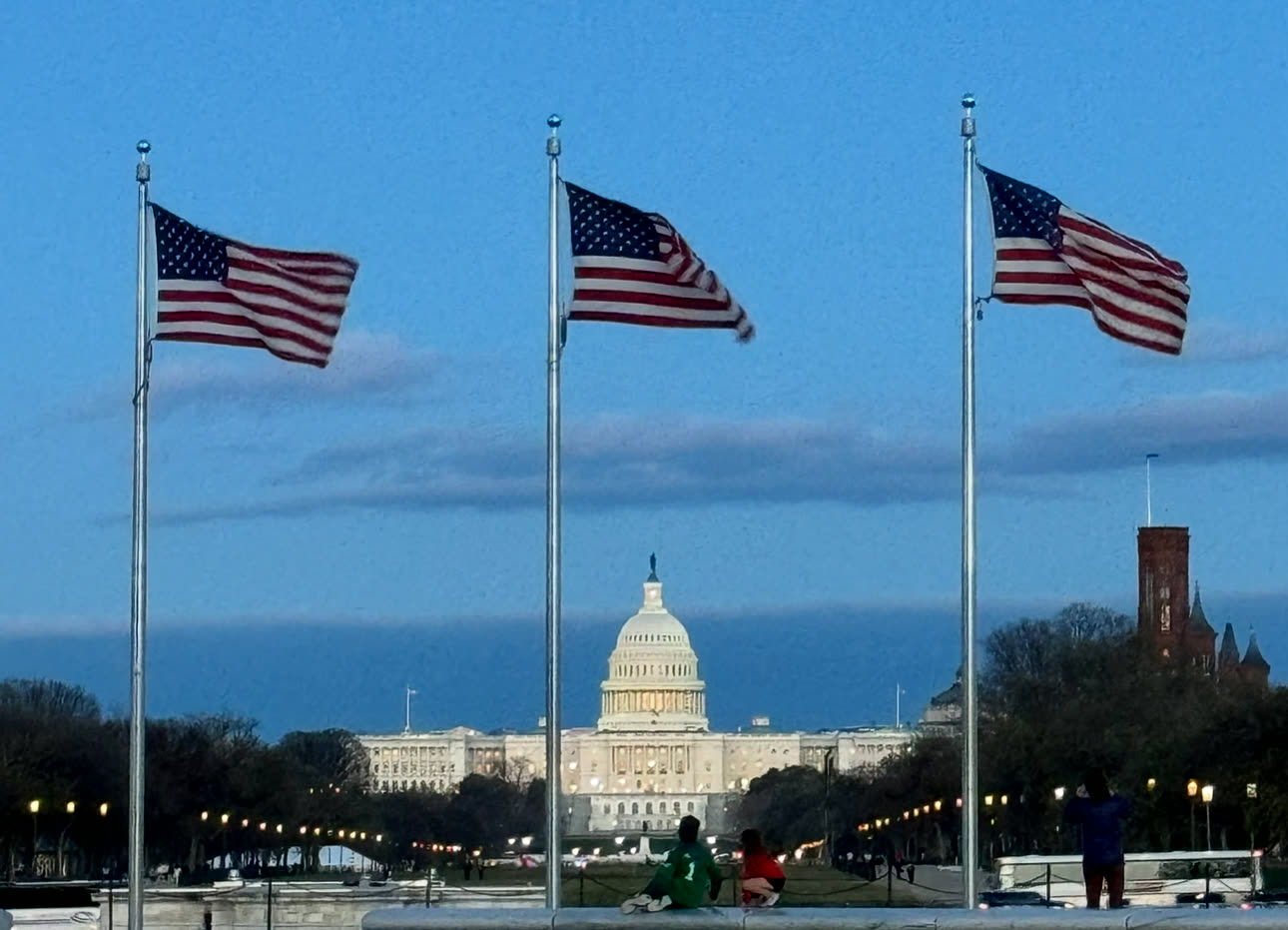 The United States Capitol behind three American flags