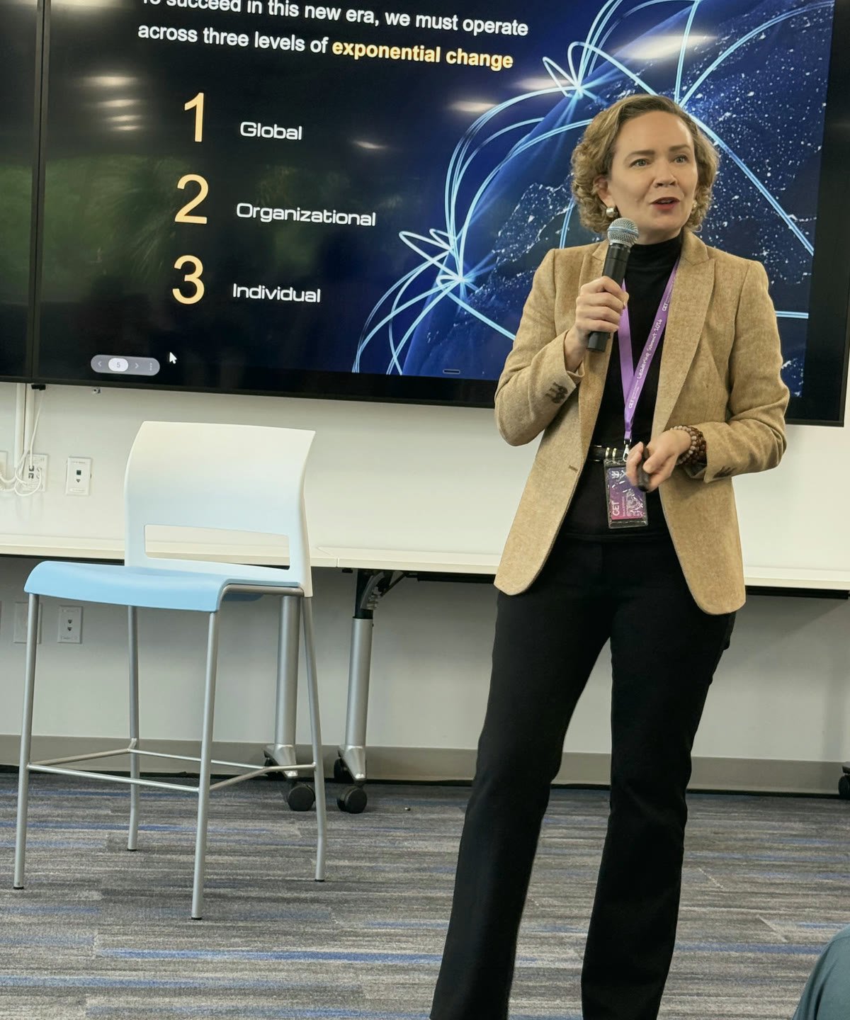 Tarja Stephens presenting to a leadership team, a slide on three levels of exponential change behind her