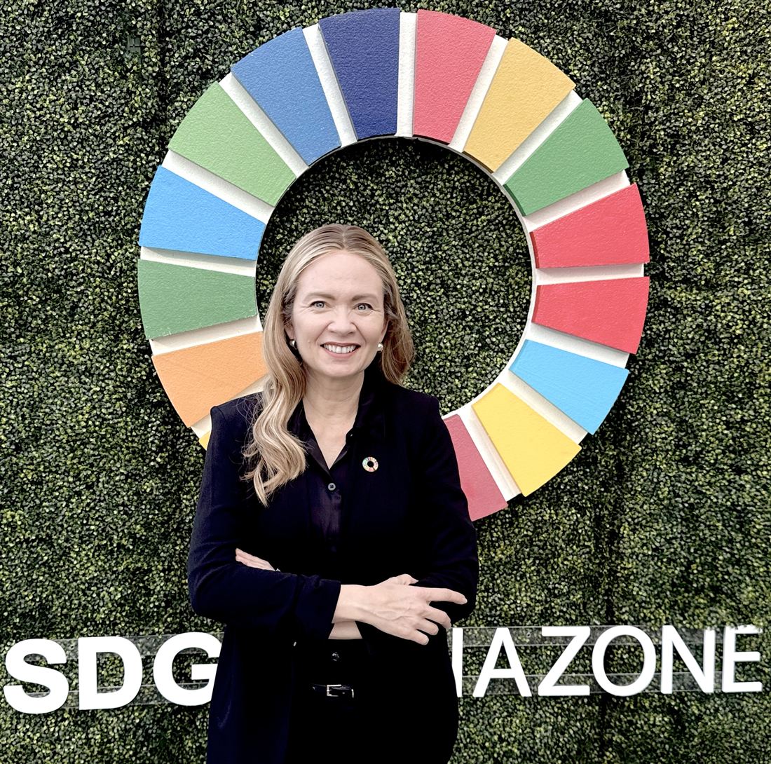 Tarja Stephens in front of the Sustainable Development Goals wheel at the SDG Media Zone