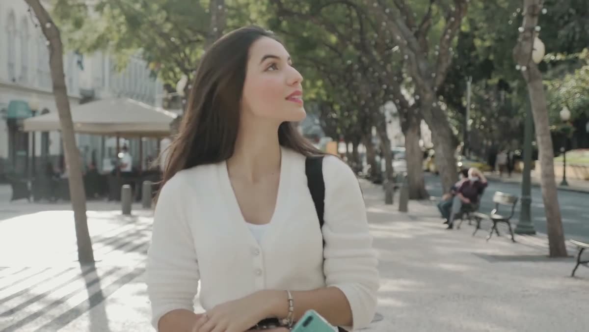 A professional walking a sunlit street with her phone in hand, from the Career Twin site.